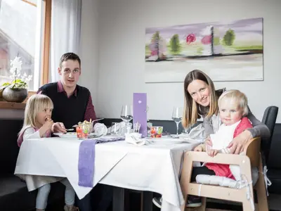 a family sitting at a table in a restaurant at Familienhotel Viktoria in Ultimo