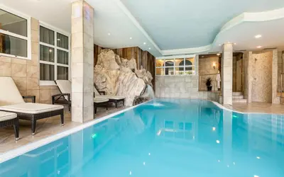 a swimming pool in a hotel with a rock wall at Familienhotel Viktoria in Ultimo