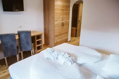 a room with a bed and a table and chairs at Hotel Pension Odles in San Martino in Badia