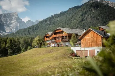 a house on a hill with a mountain in the background at Hotel Pension Odles in San Martino in Badia