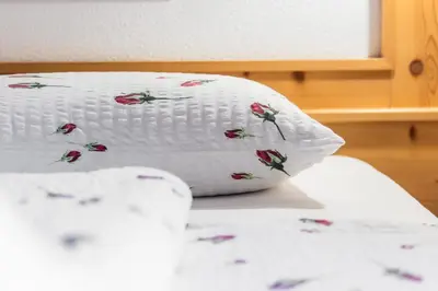 a white pillow sitting on top of a bed at Hotel Pension Odles in San Martino in Badia