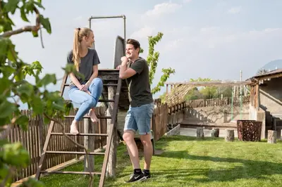 a man and a woman sitting on a ladder at Engadiner Apartments & Wines in Montagna