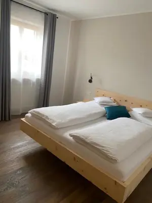 a large bed with a wooden headboard in a bedroom at Engadiner Apartments & Wines in Montagna