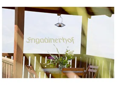a sign for an outdoor restaurant with a table with flowers at Engadiner Apartments & Wines in Montagna