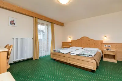 a bedroom with a bed and a desk and a bed at Hotel Resa Blancia in San Vigilio Di Marebbe