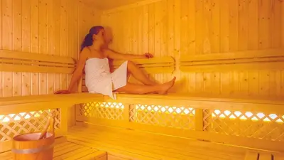 a woman is sitting in a sauna at Hotel Resa Blancia in San Vigilio Di Marebbe
