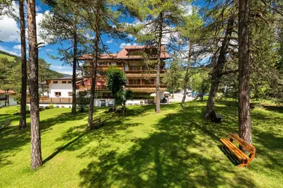 a building in the middle of a park with trees at Hotel Resa Blancia in San Vigilio Di Marebbe