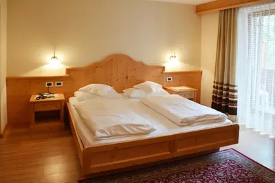 a bedroom with a large bed with white sheets at Hotel Resa Blancia in San Vigilio Di Marebbe