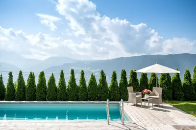 a pool with two chairs and an umbrella at Mitterstiller in Auna di Sotto