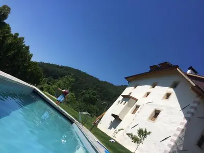 a man standing on the edge of a swimming pool next to a building at Mitterstiller in Auna di Sotto