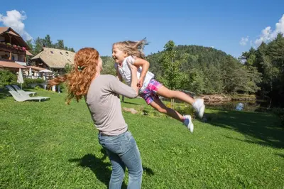 a woman holding a little girl in the grass at Hotel Weihrerhof in Soprabolzano