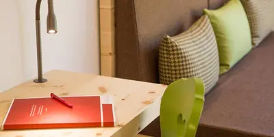 a wooden table with a book and a green chair at Hotel Weihrerhof in Soprabolzano