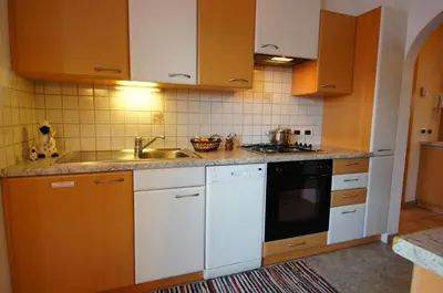 a kitchen with white cabinets and a sink at Gasthof La Pli Apartments in San Vigilio Di Marebbe