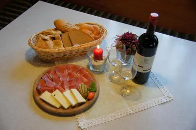 a table with a bottle of wine and a basket of cheese and bread at Gasthof La Pli Apartments in San Vigilio Di Marebbe
