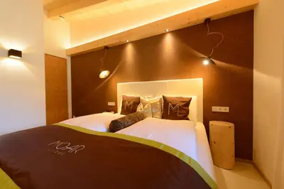 a bedroom with two beds and a brown wall at Moar Lodge in Postal