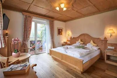 a bedroom with a large bed and a balcony at Dolomites Wellness Hotel Savoy in La Villa