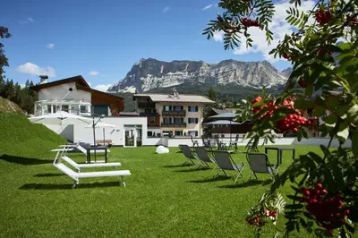 a living room with a red couch and a table at Dolomites Wellness Hotel Savoy in La Villa