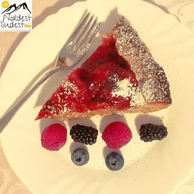 a piece of cake with berries on a plate with a fork at Camere Nordest Sudest- Conca Agordina in Agordo