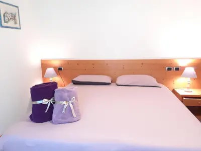 a white bed with two purple bags on it at Camere Nordest Sudest- Conca Agordina in Agordo