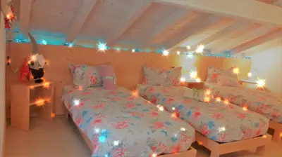 two beds in a room with christmas lights at Camere Nordest Sudest- Conca Agordina in Agordo