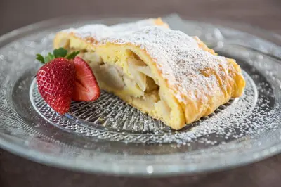 a piece of cake on a glass plate with strawberries at Hotel Jaufentalerhof in Racines