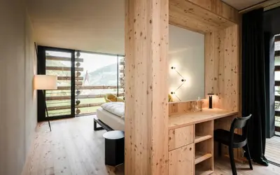 a bedroom with a bed and a desk with a mirror at Hotel Jaufentalerhof in Racines