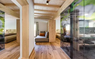 a living room with a couch and a glass wall at Hotel Jaufentalerhof in Racines