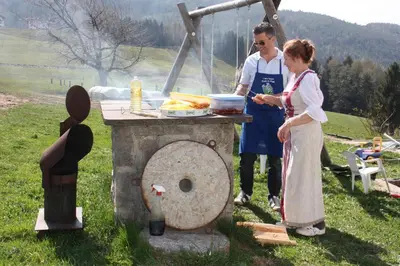 a man and a woman preparing food on a grill at Spisserhof in Chiusa