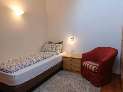 a small bedroom with a bed and a chair at Fiemme Deluxe Apartment in Castello di Fiemme