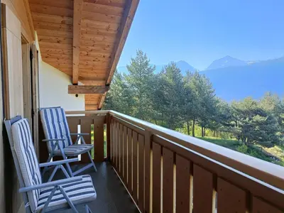 two chairs on a balcony with a view of mountains at Fiemme Deluxe Apartment in Castello di Fiemme