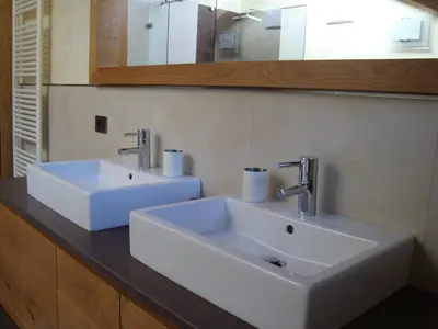 a bathroom with two white sinks and a mirror at Fiemme Deluxe Apartment in Castello di Fiemme
