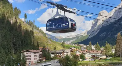 a cable car flying over a village in the mountains at Arnica in Canazei