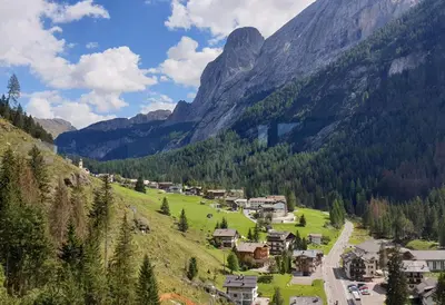 a village in a valley with a mountain in the background at Arnica in Canazei