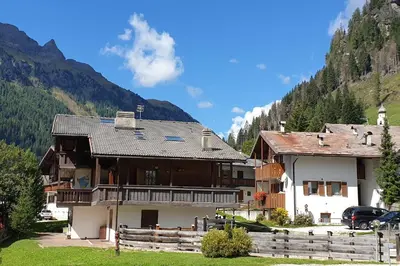 a building with a fence in front of a mountain at Arnica in Canazei