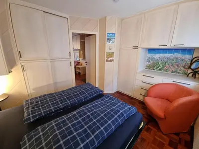 a room with two beds and a chair and a window at Arnica in Canazei