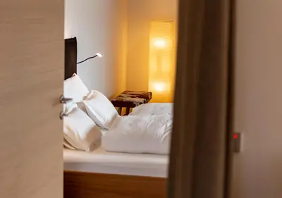 a bedroom with a bed with white sheets and a lamp at Kronplatz LOFT Bruneck in Brunico
