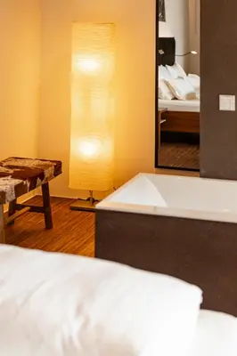 a bedroom with a bed and a lamp and a mirror at Kronplatz LOFT Bruneck in Brunico