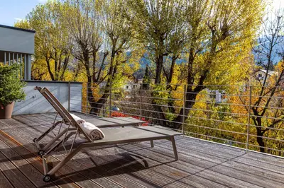 a chair on a deck with a view of trees at Kronplatz LOFT Bruneck in Brunico