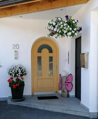 a door with a butterfly painted on it next to flowers at Appartements Oberleiter in Valdaora