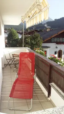 a red chair on a balcony with a table at Appartements Oberleiter in Valdaora