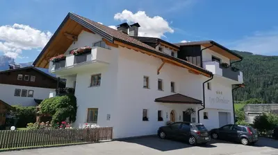 a white building with cars parked in front of it at Appartements Oberleiter in Valdaora