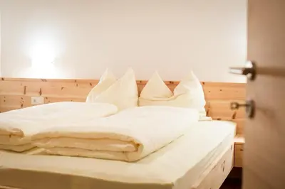 a bed with white sheets and pillows on it at Brugger Hof in Feldthurns