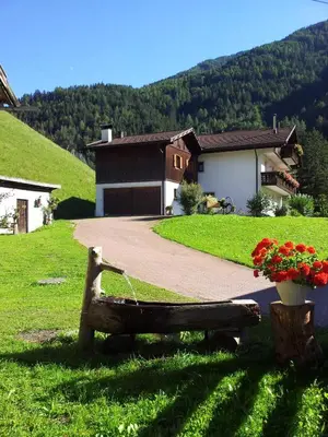 a park bench sitting in the grass in front of a house at Ferienhaus-Grünfelder in Luson