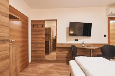 a bedroom with a bed and a desk and a tv at Pension Sunnhofer in Vilpiano