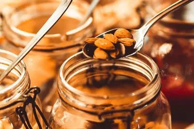 a spoon with nuts on top of a jar of honey at Pension Sunnhofer in Vilpiano