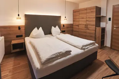 a bedroom with a large bed with white sheets and pillows at Pension Sunnhofer in Vilpiano