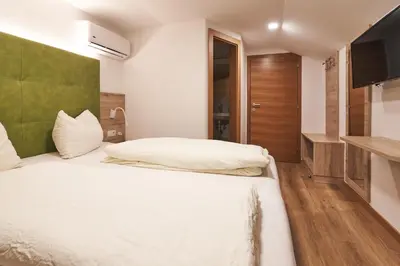 a bedroom with a white bed and a flat screen tv at Pension Sunnhofer in Vilpiano