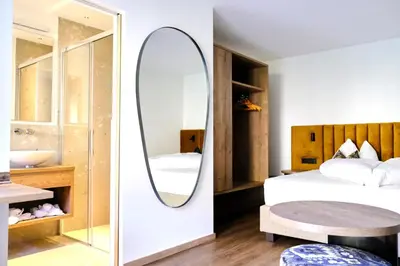 a bedroom with a mirror and a bed and a table at Pension Sunnhofer in Vilpiano
