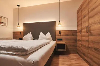 a bedroom with a large bed and wooden walls at Pension Sunnhofer in Vilpiano