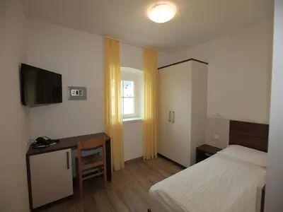 a bedroom with a white bed with an orange pillow at Hotel Stampfer B&B in Laives